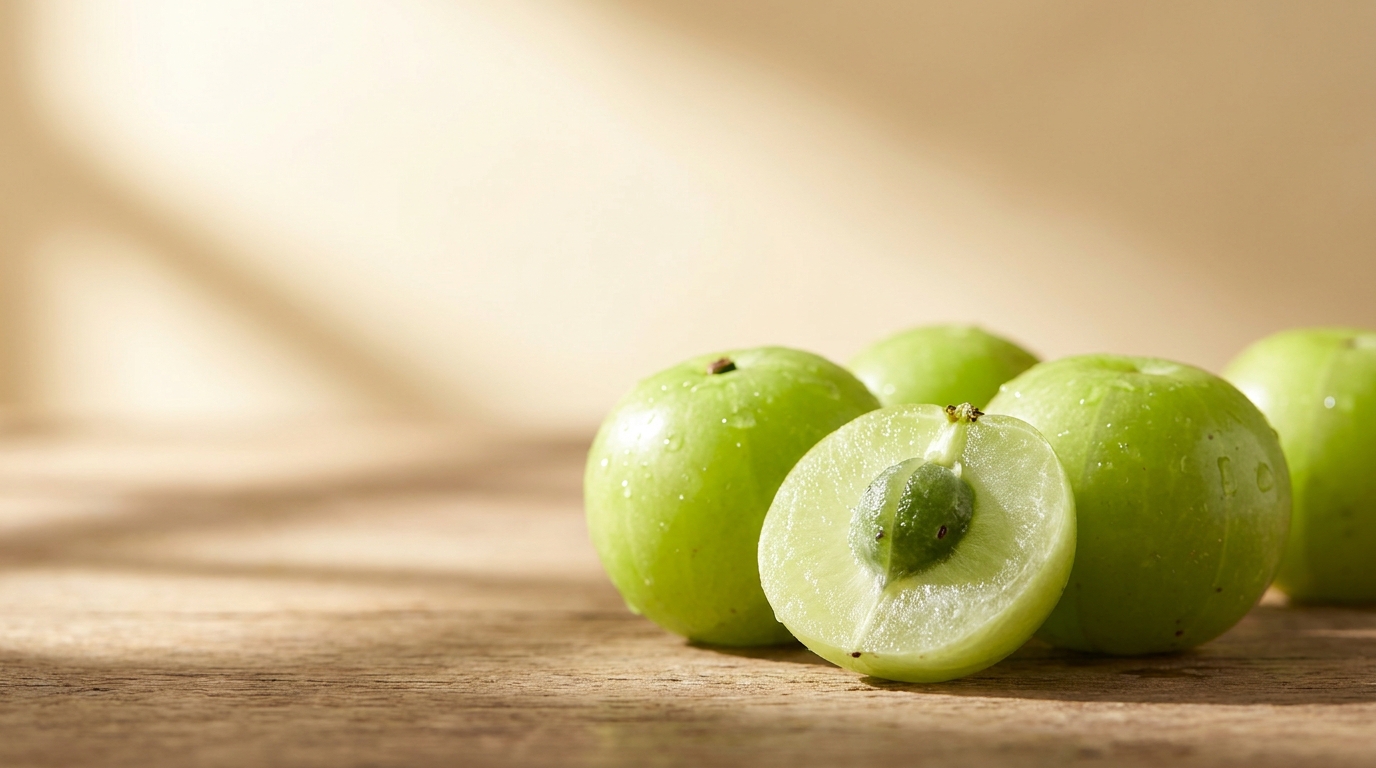 Fresh amla fruits, one cut open, on a wooden surface